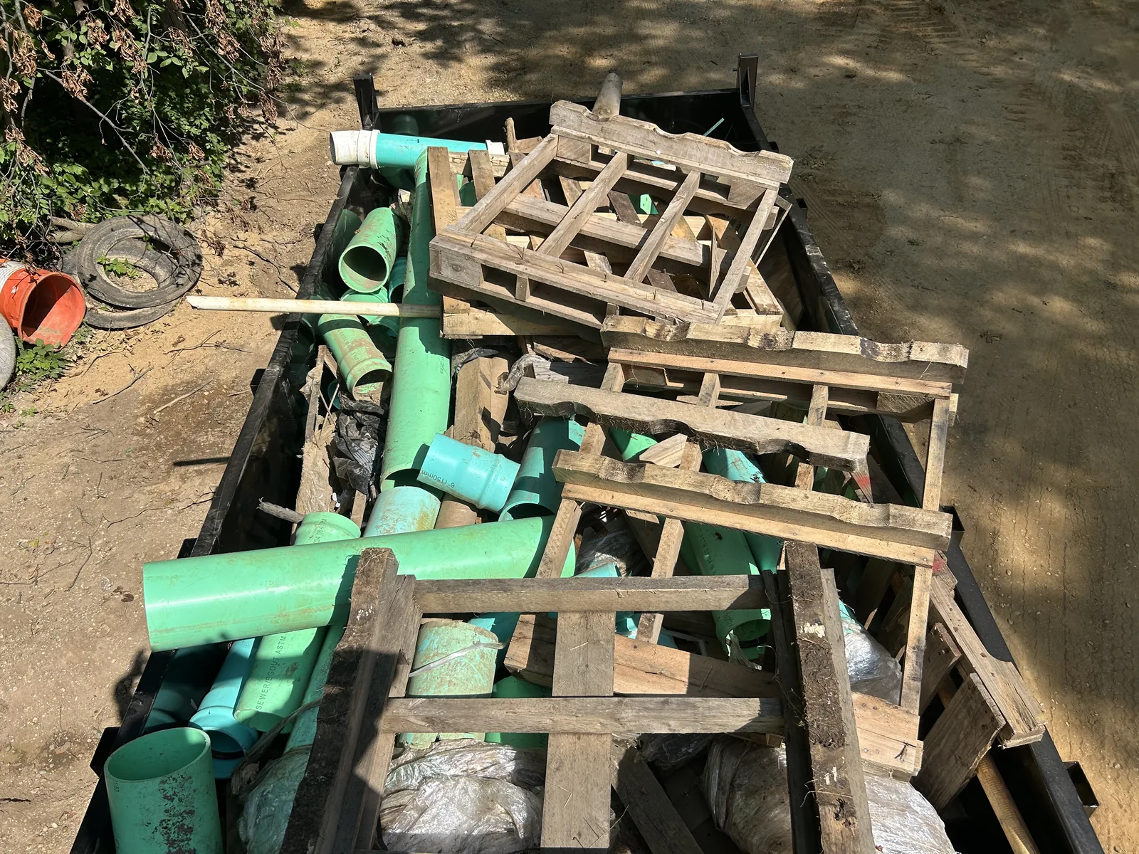 Dump trailer loaded with sewer pipe and wooden pallets