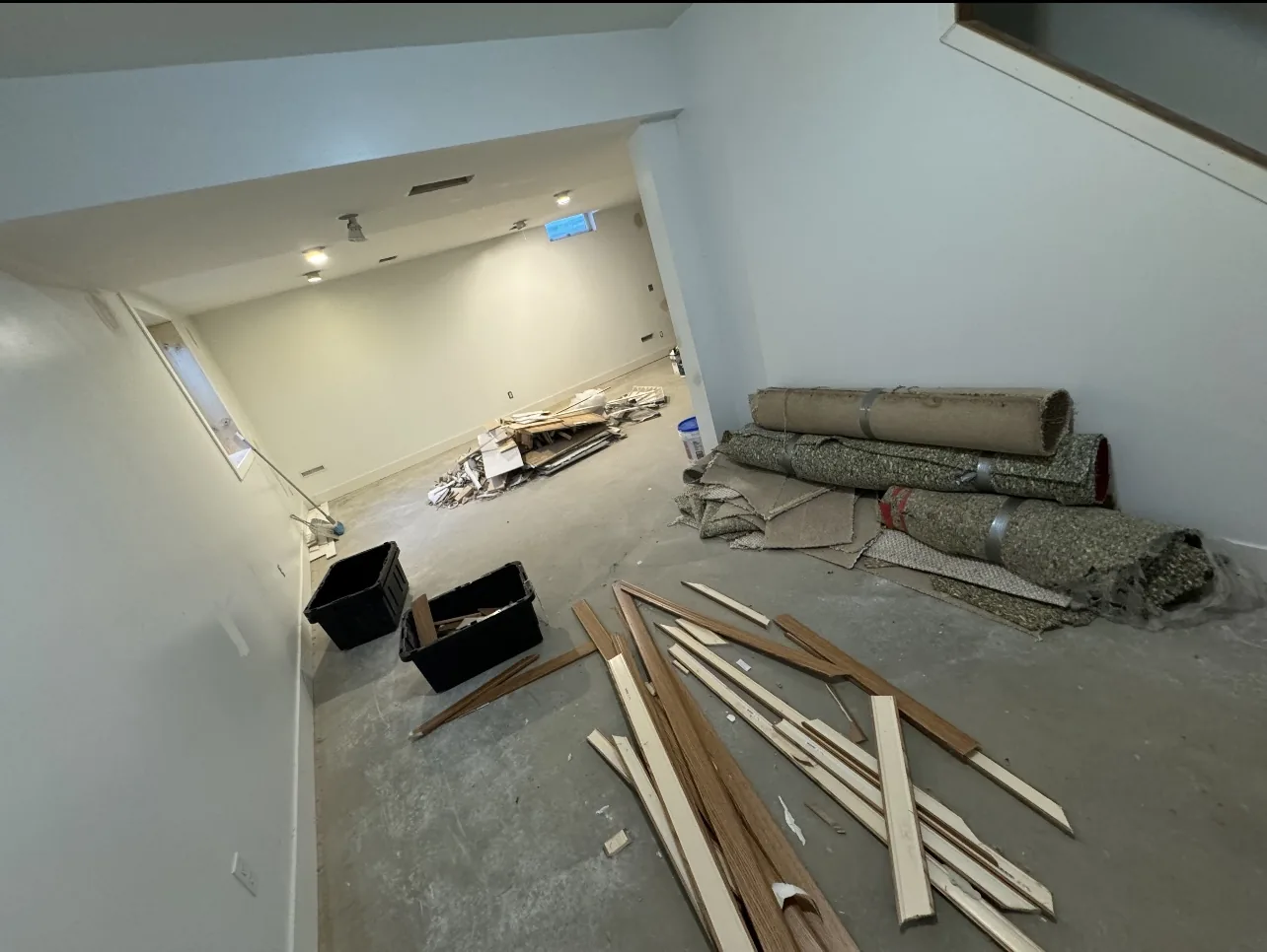 Basement with rolled carpet, tack strip and trim staged for removal